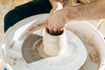 Worker making clay pot on pottery wheel at his studio