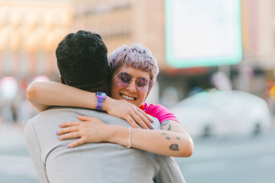Smiling woman embracing unrecognizable beloved near colorful