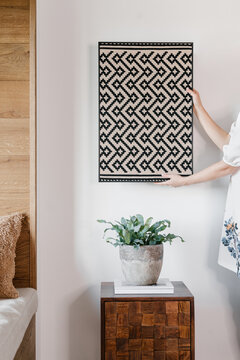Unrecognizable woman hanging knitted panel on wall