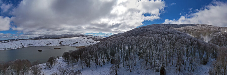 Drone shooting at 180 degrees of the Biviere lake in the heart of the Nebrodi mountains in winter. View of Etna and the Aeolian Islands. Sicily in winter. Sicilian mountains.