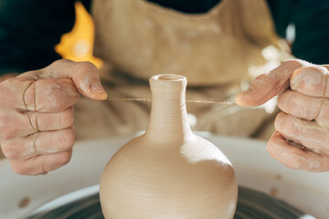Adult artist modeling jar or vase in studio on potters wheel