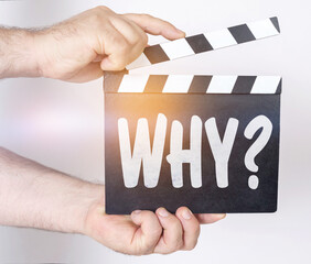 On a white background, a man holds a clapperboard in his hands on which it is written - WHY