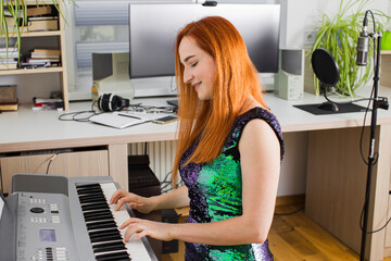 Fototapeta na wymiar The young woman is playing in the studio on a synthesizer