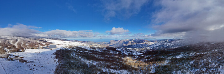 Drone shooting at 180 degrees of the Biviere lake in the heart of the Nebrodi mountains in winter. View of Etna and the Aeolian Islands. Sicily in winter. Sicilian mountains.