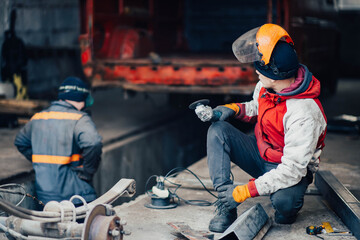 Fototapeta premium male plant worker in a protective helmet and with a grinder looks questioningly. Enterprise safety concept