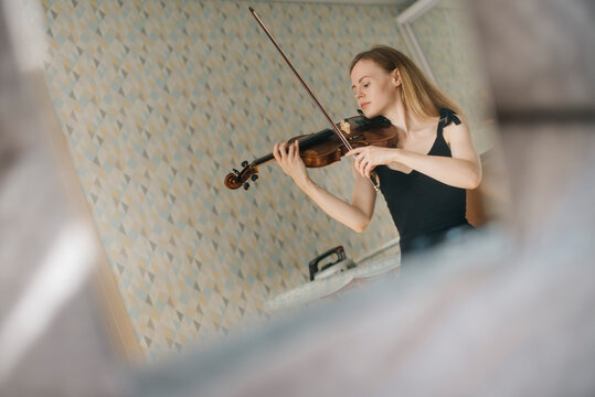 A beautiful woman plays the violin at home