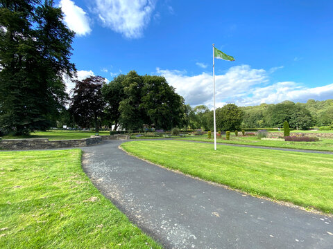 Park area, close to, Bradford Road, with old trees, green lawns, and a blue sky in, Halifax, Yorkshire, UK
