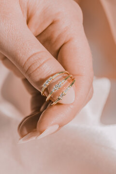 Woman Holding Multiple Rings With Her Finger, Silky Background