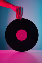 Hand hold retro vinyl disc with neon lights. Vintage music background