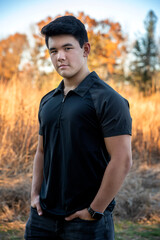 Outdoor lifestyle portrait of handsome young man wearing short sleeve black shirt looking at camera