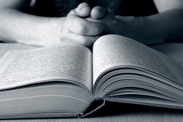 Close up of an open book. A man reads a prayer book at home in the evening.