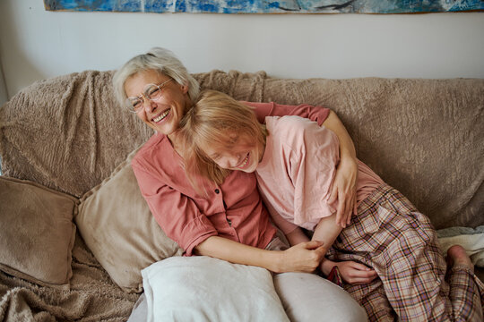 Active age ageless senior woman with daughter on house sofa