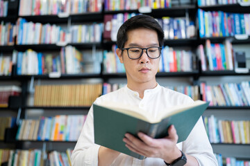 A man is reading a book in the university library.