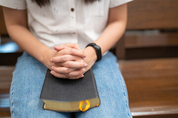 Obraz premium Asian woman is reading the Holy Bible and praying in a Christian church.