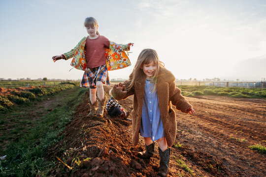 three kids walking on a dirt laneway