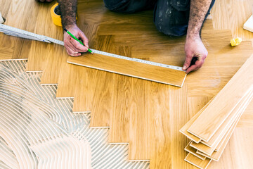 Handwerker verlegt parkettboden in einem Haus.
