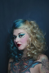 Portrait of beautiful tattooed young woman with fancy makeup and hairdo