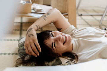 Young happy fwoman lying onf floor relaxing in studio