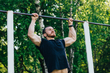 Fototapeta premium Closeup of strong athlete doing pull-up on horizontal bar.