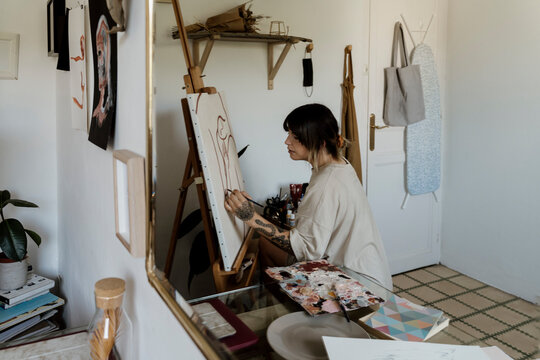 Young female artist painting canvas on her studio