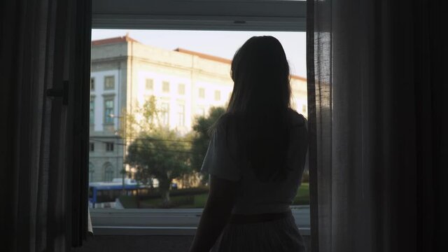 Girl looking out of a window, brushing her teeth