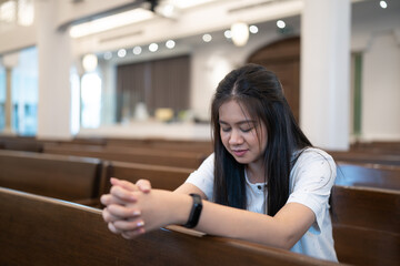 An Asian woman praying in a Christian church.