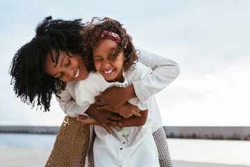 Cheerful mother and child hugging on street