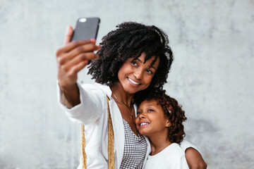 Tender mother and daughter taking selfie on mobile phone