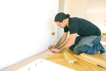 Handwerker verlegt parkettboden in einem Haus.
