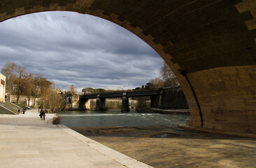 Arch of Roman bridge seen from the quay of the Tiber river to the Tiber Island.