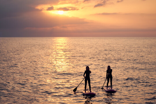 Unrecognizable women on surfing boards in sea