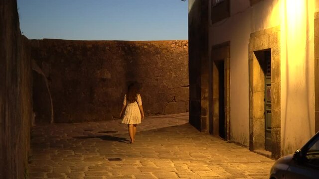 Girl walking through the street at night in Porto, Streetlights