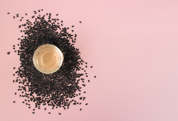 Fresh sesame seed and cosmetics sesame oil on pink background. Top view. Beauty flatlay.