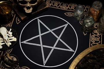 Huge pentagram symbol on the table. Mystic background with occult and magic objects on ritual altar. Human skull, bones, old book and ingridients for rituals.