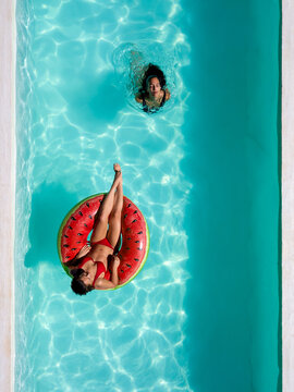 Drone shot of two friends in the pool with An inflatable