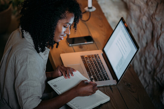 Positive ethnic freelancer making notes