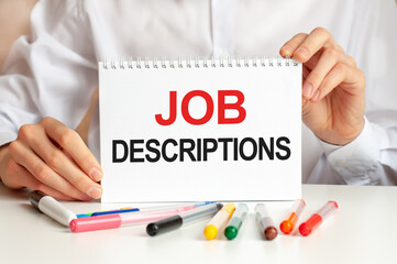 A sheet of paper with text job descriptions, multicolored markers on a white table. Business and...