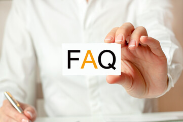 A woman in a white shirt holds a piece of paper with the text: faq. faq - frequency asked...