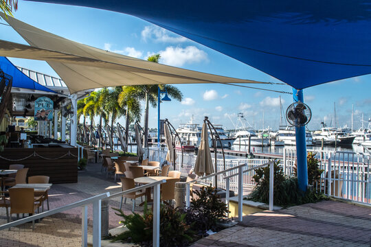 Downtown historic Stuart, Florida. Restaurants on the St. Lucie River with outdoor eating areas covered with blue awnings, yachts in the marina, lifestyle at the waterfront town in eastern Florida