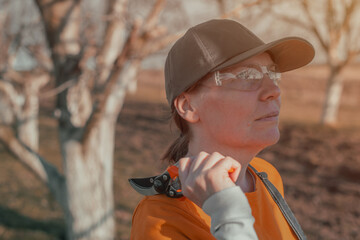 Female gardener with hand pruner in walnut orchard, woman farmer using pruning shears