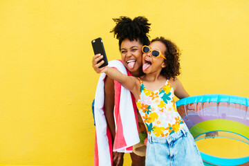 Funny black mother and daughter taking selfie in summer