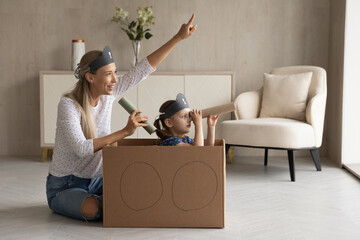 Loving young Caucasian mom and small daughter play pirate game in living room at home. Caring...