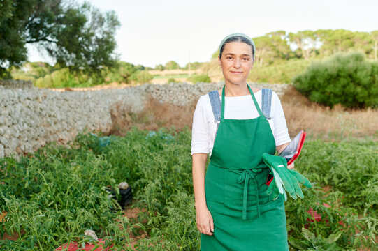 Smiling woman standing in her vegetable garden