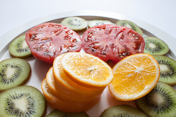 Still life of kiwi, lime and tomato fruit slices on gray background. Flat lay.