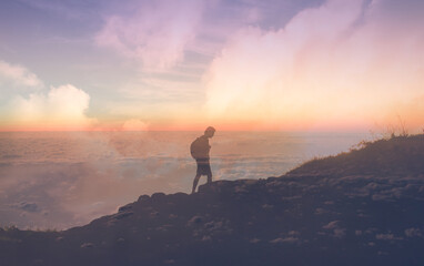 Young man climbing a mountain walking un the clouds. 