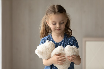 Cute little 7s girl kid hold fluffy animal toy have fun engaged in playful activity at home on...