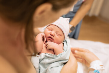 Adorable newborn baby girl sleeping in mothers arms. Now life and childbirth concepts.