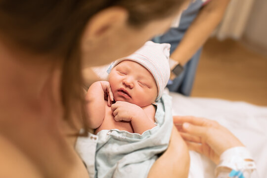 Adorable Newborn Baby Girl Sleeping In Mothers Arms. Now Life And Childbirth Concepts.