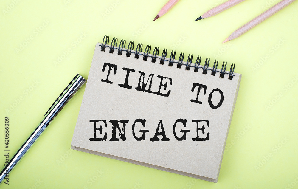 Poster time to engage text on the notebook with pen on yellow background