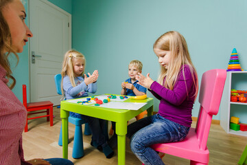 The kids sit at the desk and molding clay